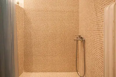 a shower in a bathroom with a tile wall at Acropolis Steps, City Apartment in Athens