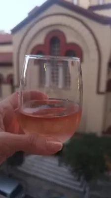 a hand holding a glass of wine in front of a church at GAYA apartments in Athens