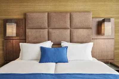 a bedroom with a bed with two blue pillows at Arion Athens Hotel in Athens