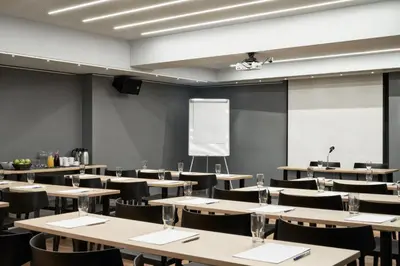 an empty lecture room with tables and chairs at Arion Athens Hotel in Athens