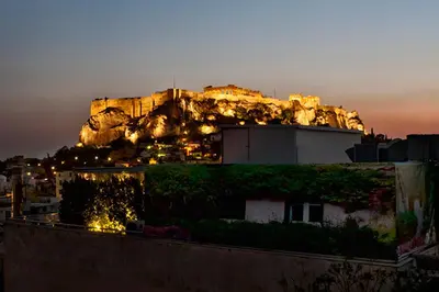 a castle on top of a mountain at night at Hermes Hotel in Athens