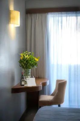a room with a table with a vase of flowers and a window at Hermes Hotel in Athens