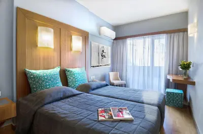 a hotel room with two beds and a magazine on top of it at Hermes Hotel in Athens