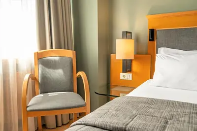 a bedroom with a bed and a chair next to a window at Plaka Hotel in Athens