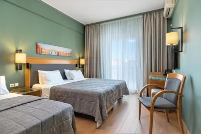 a hotel room with two beds and a desk and a window at Plaka Hotel in Athens