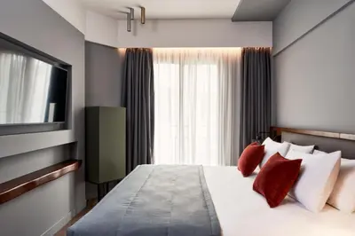 a bedroom with a bed with red pillows and a television at Hotel Achilleas in Athens