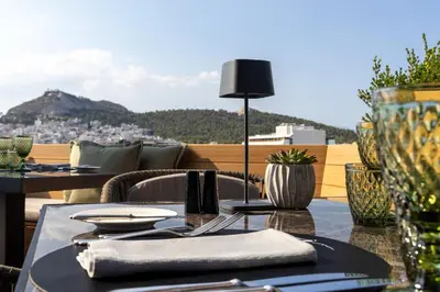 a table on a balcony with a view of a city at Divani Caravel in Athens