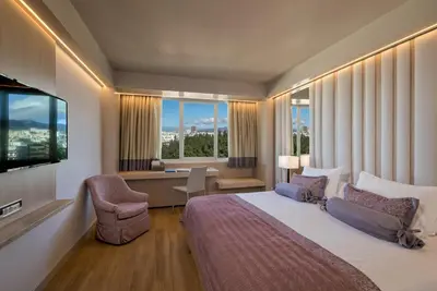a hotel room with a bed and a desk and window at Divani Caravel in Athens