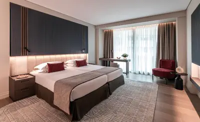 a bedroom with a large bed and a red chair at NJV Athens Plaza in Athens