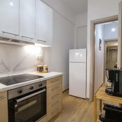 a kitchen with white cabinets and a white refrigerator at Classy Apartment in Athens in Athens