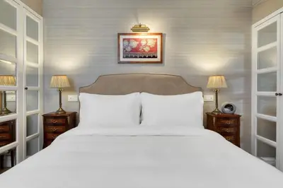 a bedroom with a large white bed with two lamps at King George, a Luxury Collection Hotel, Athens in Athens