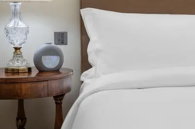 a bed and a clock on a table next to a bed at King George, a Luxury Collection Hotel, Athens in Athens