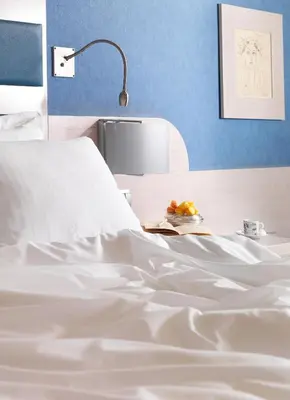 a white bed with a lamp and a plate of fruit at Holiday Inn Athens Attica Av, Airport W. by IHG in Athens