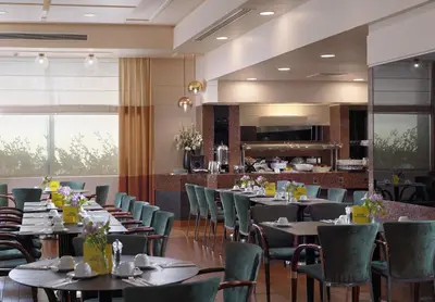 a restaurant with tables and chairs and a bar at Holiday Inn Athens Attica Av, Airport W. by IHG in Athens