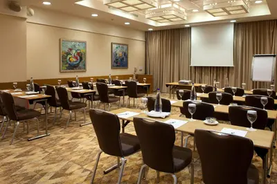a conference room with tables and chairs and a screen at Holiday Inn Athens Attica Av, Airport W. by IHG in Athens