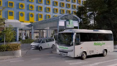 a small white car parked next to a bus stop at Holiday Inn Athens Attica Av, Airport W. by IHG in Athens