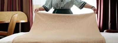 a woman is standing next to a pillow on a bed at Holiday Inn Athens Attica Av, Airport W. by IHG in Athens