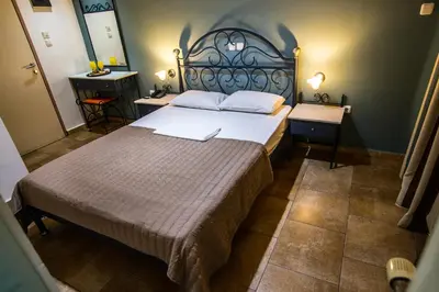 a bedroom with a large bed and two tables at Anita Hotel in Piraeus