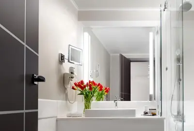 a bathroom with a sink and a vase of red flowers at Holiday Suites in Athens