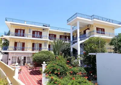 a large yellow building with balconies and a courtyard at Hotel Karyatides in Agia Marina Aegina