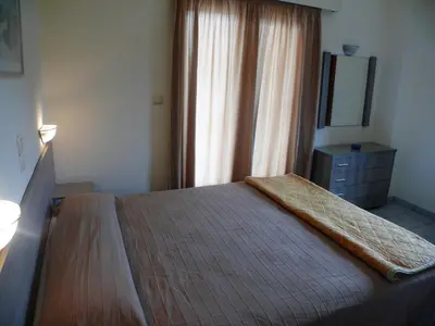 a bedroom with a bed with a dresser and a mirror at Hotel Karyatides in Agia Marina Aegina