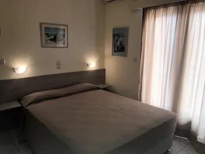 a bedroom with a bed and a large window at Hotel Karyatides in Agia Marina Aegina