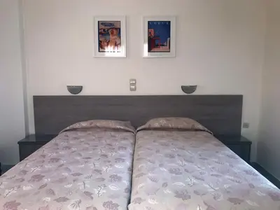 a bed in a bedroom with two pictures on the wall at Hotel Karyatides in Agia Marina Aegina