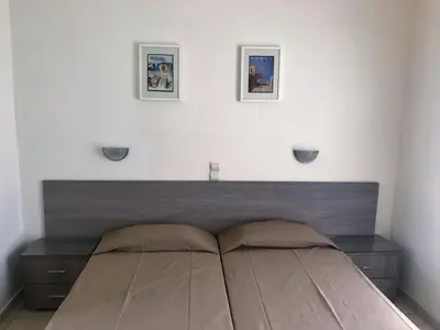 a bed in a bedroom with two pictures on the wall at Hotel Karyatides in Agia Marina Aegina