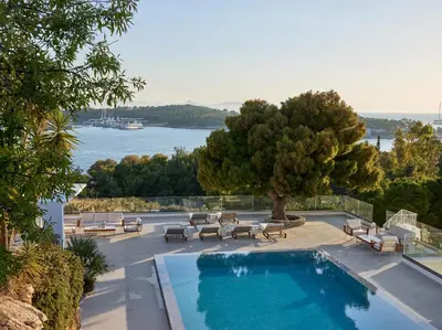 a swimming pool with chairs and a tree and water at The Roc Club, A Grecotel Hotel to Live in Athens