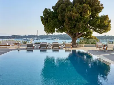 a large swimming pool with chairs and a tree at The Roc Club, A Grecotel Hotel to Live in Athens