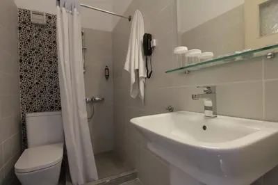 a white bathroom with a sink and a toilet at Pan Hotel in Athens