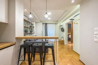 a kitchen with a wooden table and stools at Pame Rentals - Walk Distance To Acropolis with A Charming Design in Athens