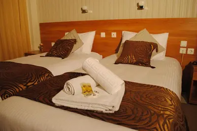 two beds in a hotel room with towels on them at Hotel Ideal in Piraeus