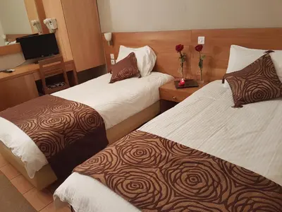 a hotel room with two beds and a television at Glaros Hotel in Piraeus