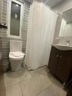 a bathroom with a white shower curtain and a toilet at Glaros Hotel in Piraeus