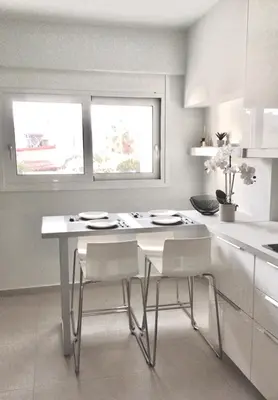 a white kitchen with a table and two windows at ATHENS RIVIERA Grand Panoramic Villa II Lagonissi in Lagonissi