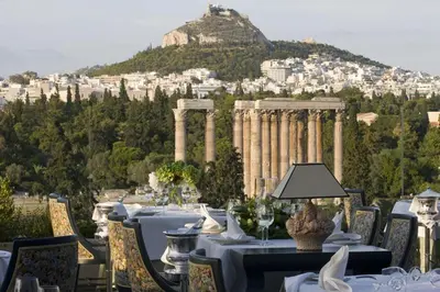 a restaurant with tables and chairs with a view ofhens at Royal Olympic Hotel in Athens
