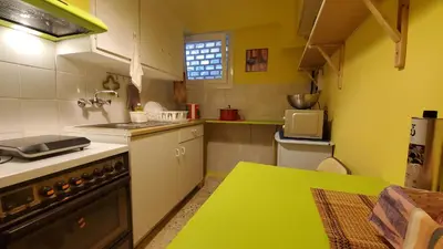 a kitchen with a stove and a green table at Sakura Hut opposite the Panathenaic Stadium in Athens