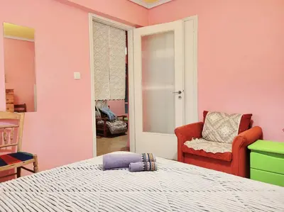 a bedroom with pink walls and a bed and a chair at Sakura Hut opposite the Panathenaic Stadium in Athens