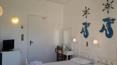 a bedroom with two beds and a sink and a mirror at Rachel Hotel in Agia Marina Aegina