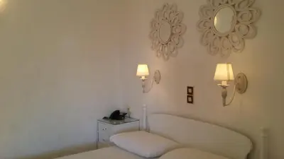 a white room with a bed and a mirror at Rachel Hotel in Agia Marina Aegina