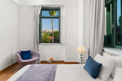 a bedroom with a bed and a window and a chair at Athenaeum Eridanus Luxury Hotel in Athens