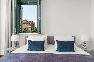 a bedroom with a bed with blue pillows and a window at Athenaeum Eridanus Luxury Hotel in Athens
