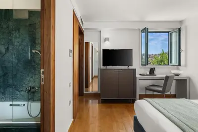 a hotel room with a bed and a television and a tub at Athenaeum Eridanus Luxury Hotel in Athens
