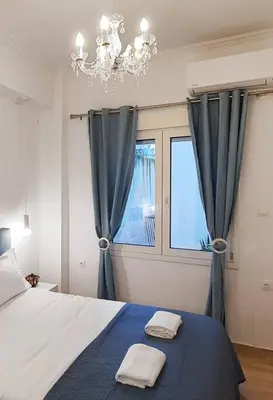 a bedroom with a bed and a chandelier and a window at Acropolis Thisio Apartment 2 bedrooms 2 bathrooms in Athens