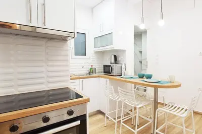 a kitchen with white cabinets and a table and chairs at Acropolis Thisio Apartment 2 bedrooms 2 bathrooms in Athens