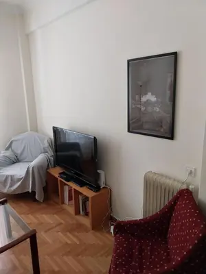 a living room with a tv and a chair at Park-view apartment in Athens