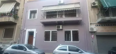 two cars parked in front of a purple building at John's Athenian Beauty 45m2 , Metro 7' in Athens