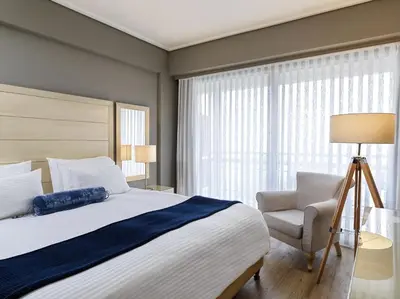a bedroom with a large bed and a chair at Sea View Cityscape Hotel in Athens