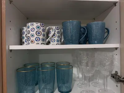a shelf filled with blue and white cups and wine glasses at Cozy apartment near the city center and beaches in Athens